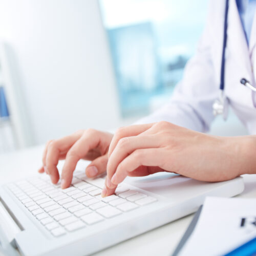 Close-up of hands of a nurse typing on laptop
