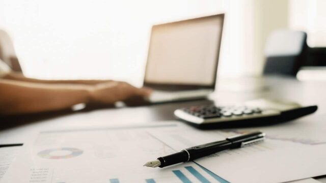 Business concept with copy space. Office desk table with pen focus and analysis chart, computer, notebook, cup of coffee on desk.Vintage tone Retro filter, selective focus.