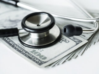 Closeup of cash and a stethoscope healthcare and expenses concept