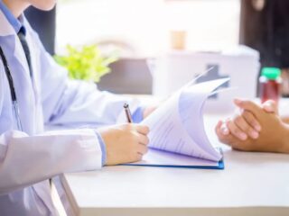 doctor-man-consulting-patient-while-filling-up-application-form-desk-hospital_1150-12966